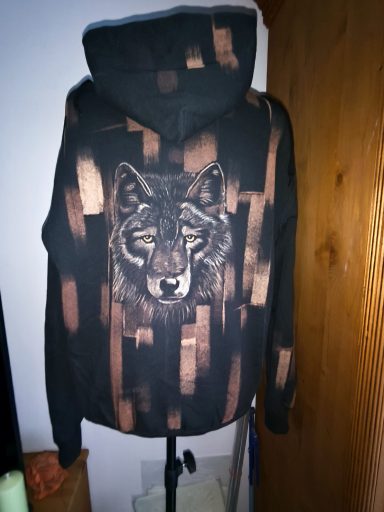 Wolfgeheul im Waschsalon Hoodie mit Wolfskopf auf der Rückseite, vorne eine Wolfspfote. Graphischer Hintergrund, der sich auf dem Ärmel und der Kapuze wiederholt