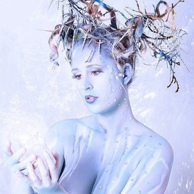 Queen of Winter Studiopainting Eiswelt in blau und weiß. Mit einem Eiskristall in der Hand und Winterzweigen mit Eiszapfen in der Hochsteckfrisur.